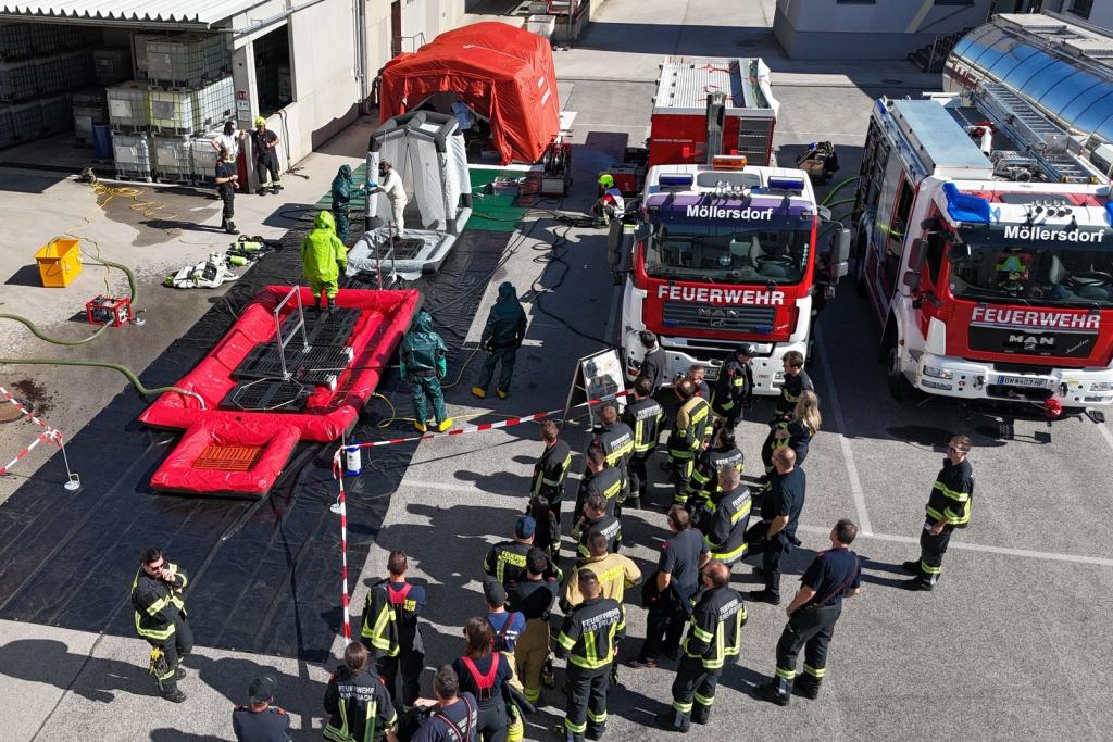 FF Wiener Neustadt: Ausbildungs-Vormittag – Schwerpunkt „Dekontamination“ - Feuerwehrmitglieder mit Deko-Straße und Fahrzeugen auf  Betriebsgelände
