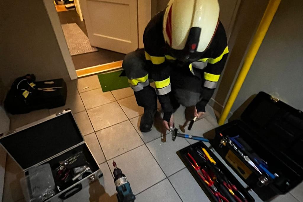 FF Neusiedl: Türöffnung aufgrund eines medizinischen Notfalls - Feuerwehrmann mit Werkzeug vor geöffneter Tür